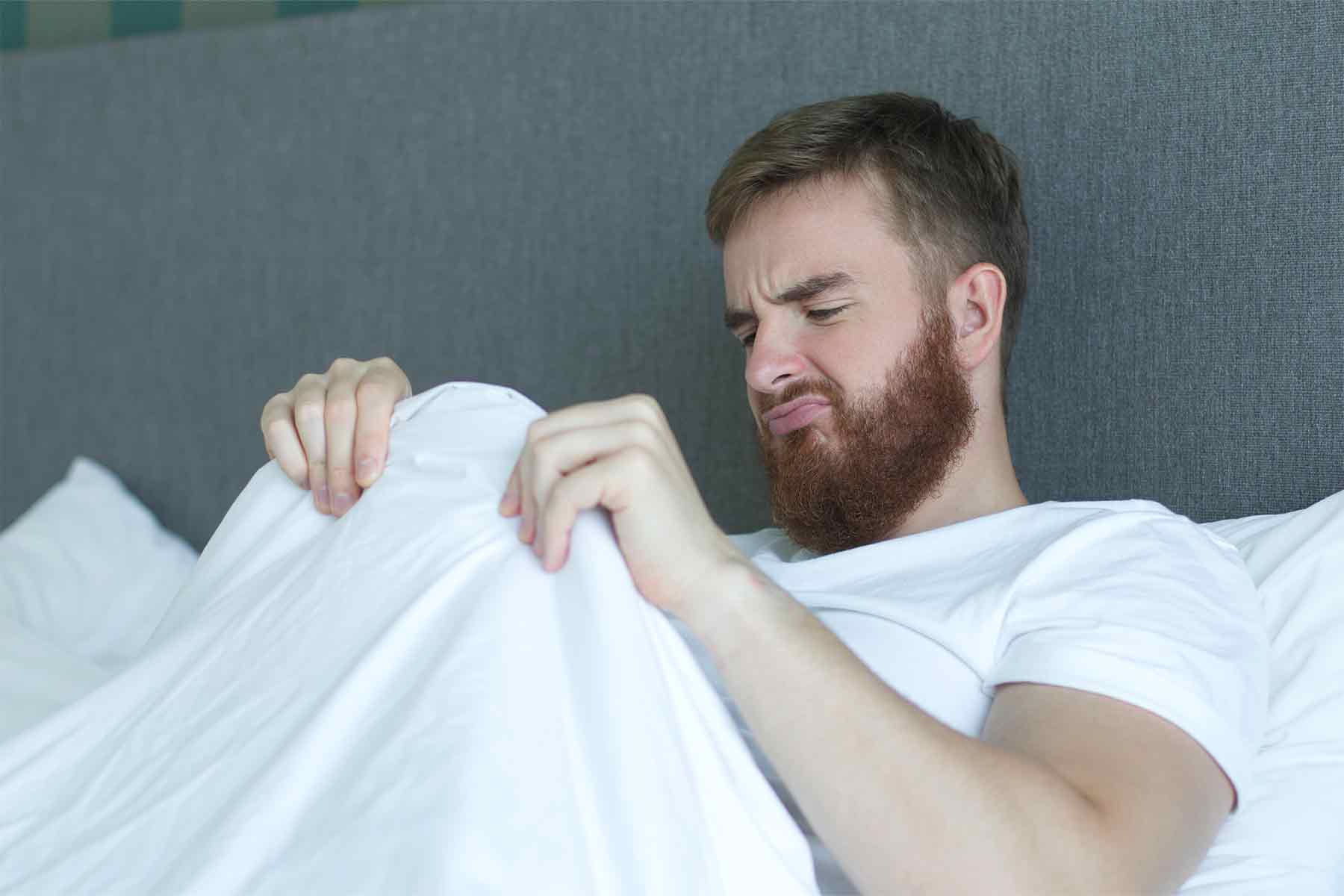 Hombre en la cama mirando sus genitales